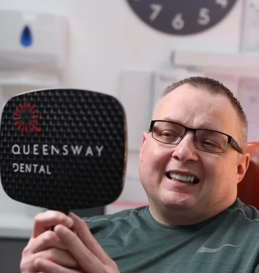 A patient admiring his restored smile at Queensway Dental A patient admiring his restored smile at Queensway Dental